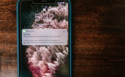 Close-up of a smartphone displaying a bank alert notification on a wooden table.
